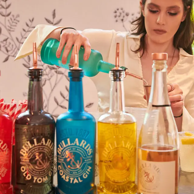 An image of a bar with a lady pouring a shot of Bullards Gin