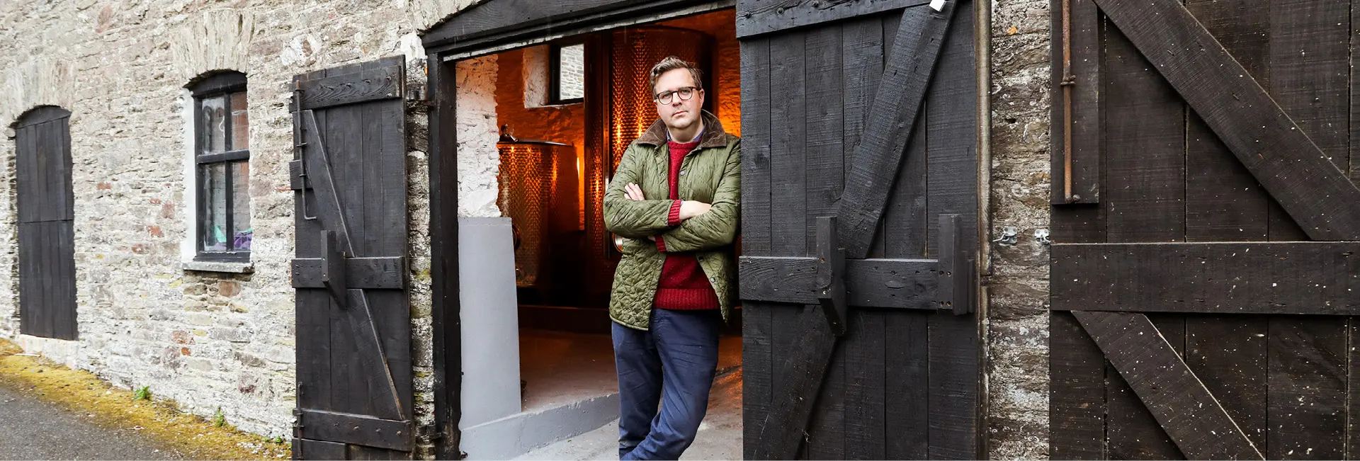 Hattiers Rum founder Philip Everett-Lyons standing between two barn doors of a distillery