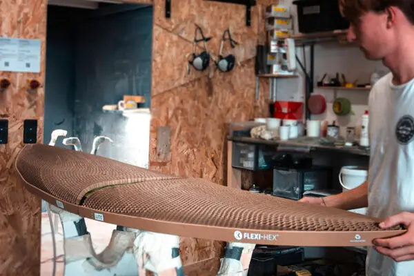 Flexi-Hex plastic-free protective surfboard packaging being placed on a Wyve surfboard in a shaping bay by a shaper