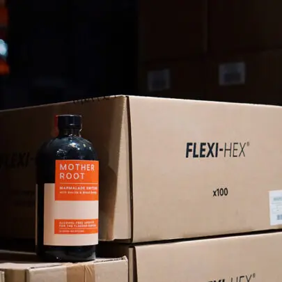 A photo of Mother Root alcohol-free bottle next to packaging in a warehouse