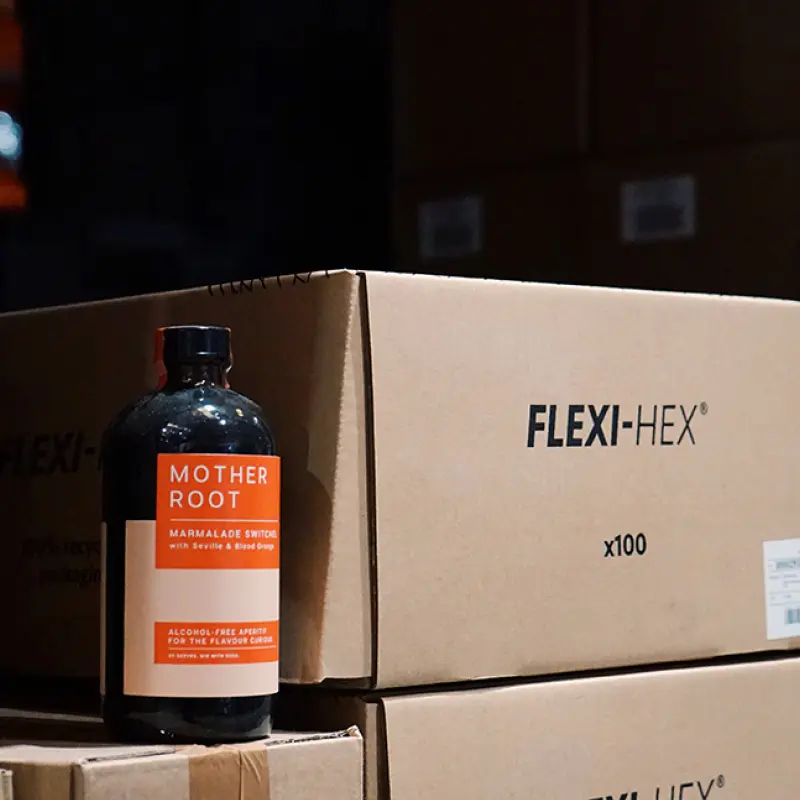 A photo of Mother Root alcohol-free bottle next to packaging in a warehouse