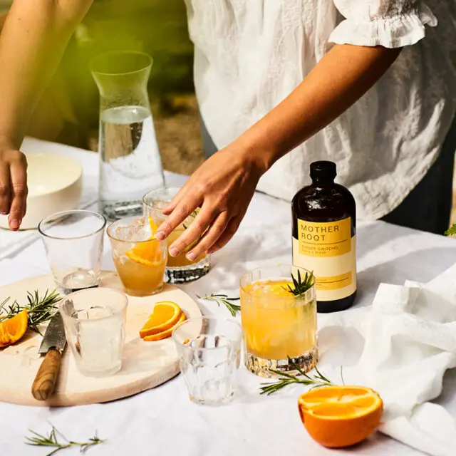 An outdoor scene with a white table cloth making non alcoholic drinks with Mother Root