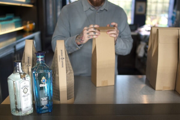 A photo of an employee at Bombay Sapphire Distillery packing up their online orders of Gin bottles in protective Flexi-hex Pinch Top boxes and Slender capsules