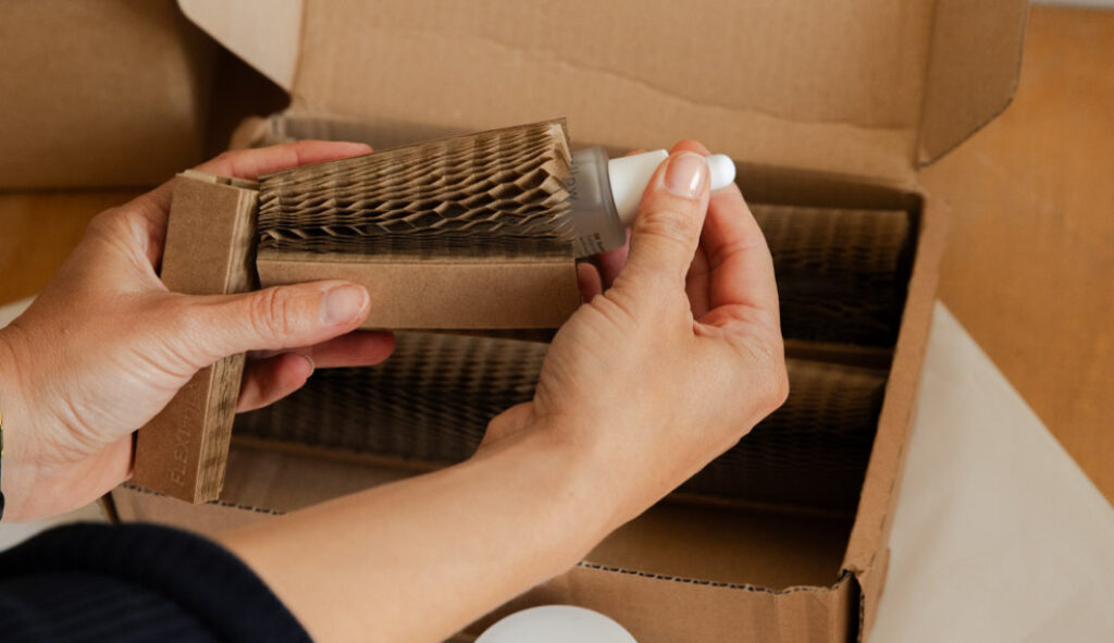 A woman placing a beauty product by Mellow Noir being placed inside a Flexi-Hex protective paper sleeve